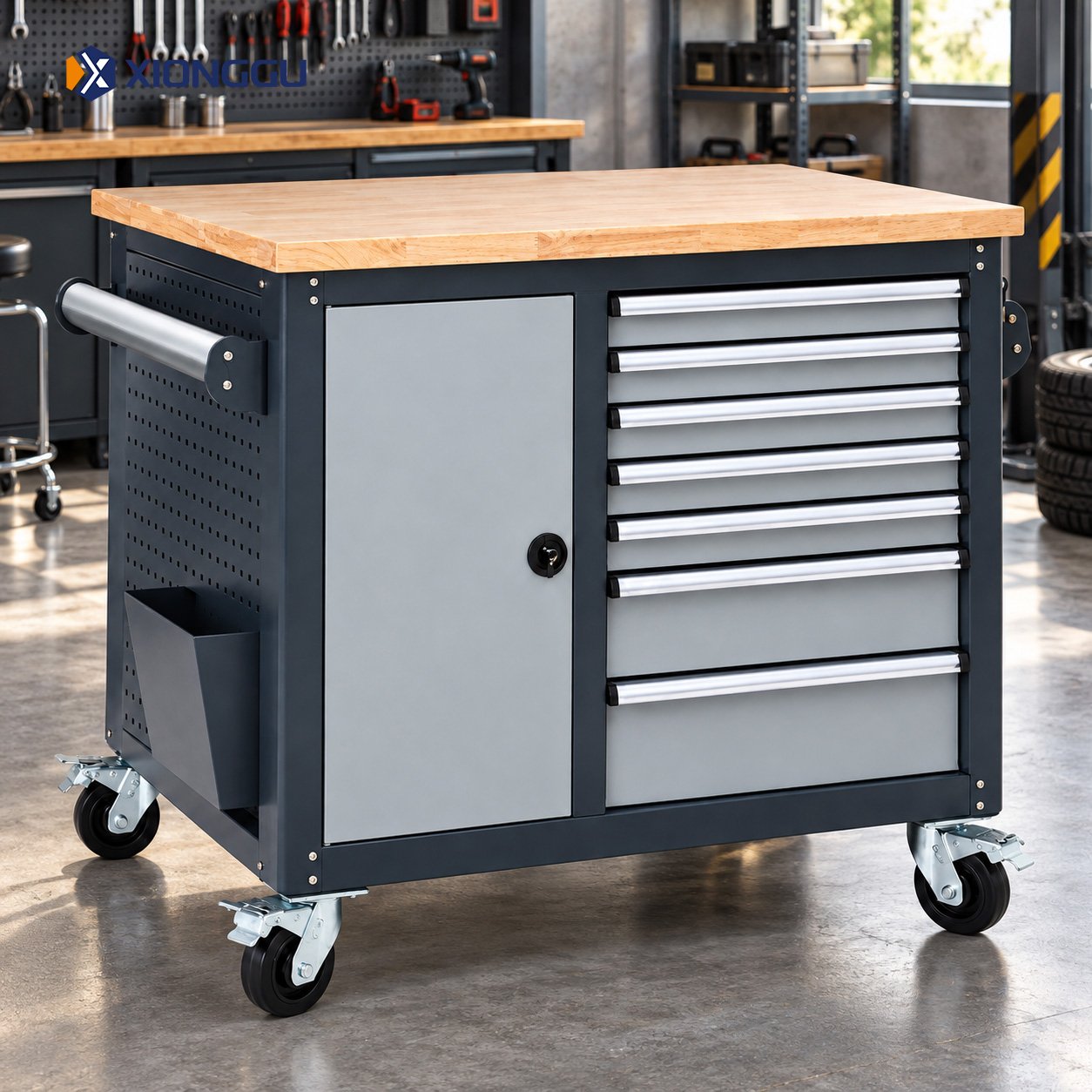 Dark grey tool trolley with silver drawers, open storage shelves, a wooden worktop and caster wheels in a workshop